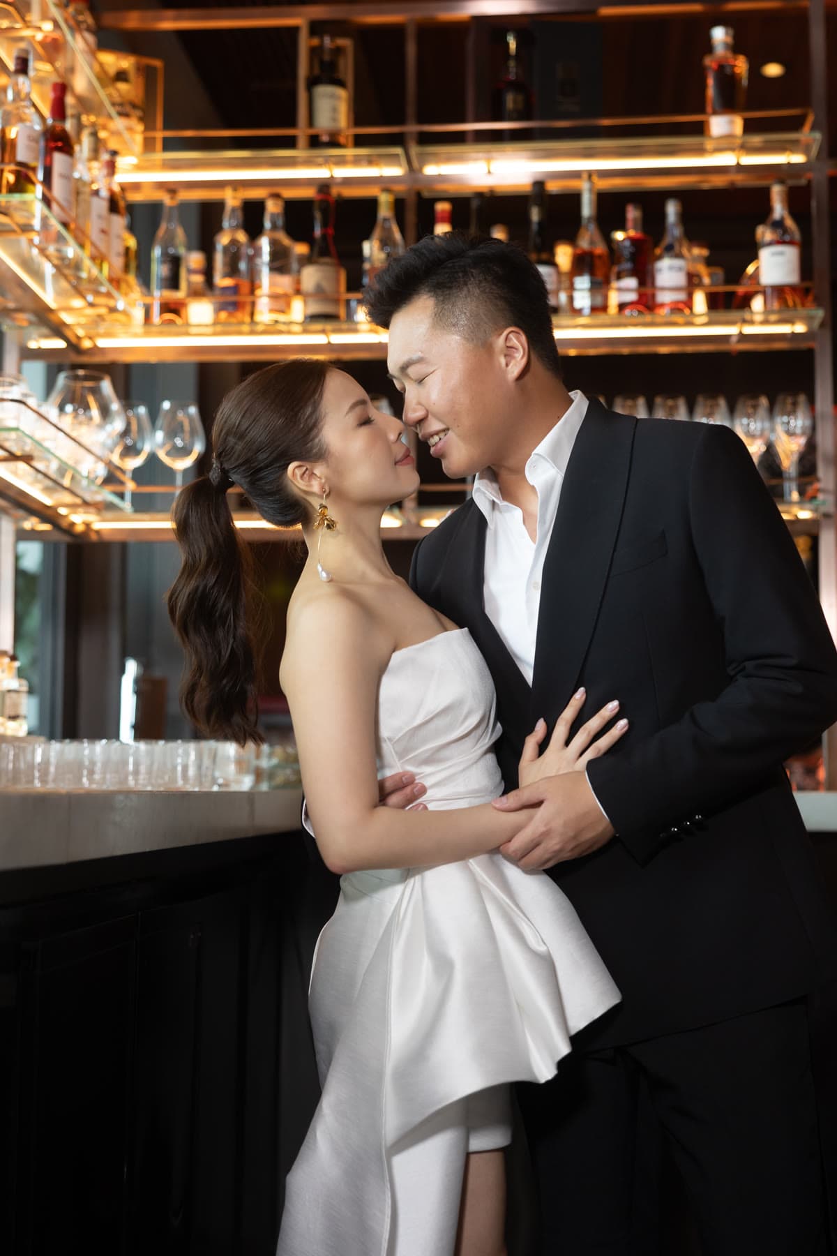 Natalie and Bryan sharing an intimate moment beside a warmly lit bar