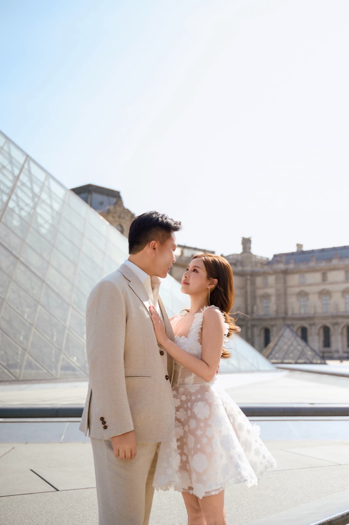 Natalie and Bryan looking at one another beside the Louvre Pyramid