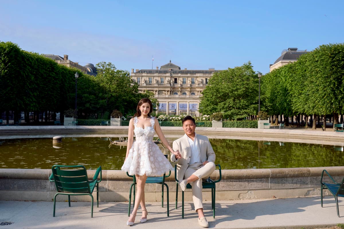 Natalie and Bryan standing together beside a formal garden and palace