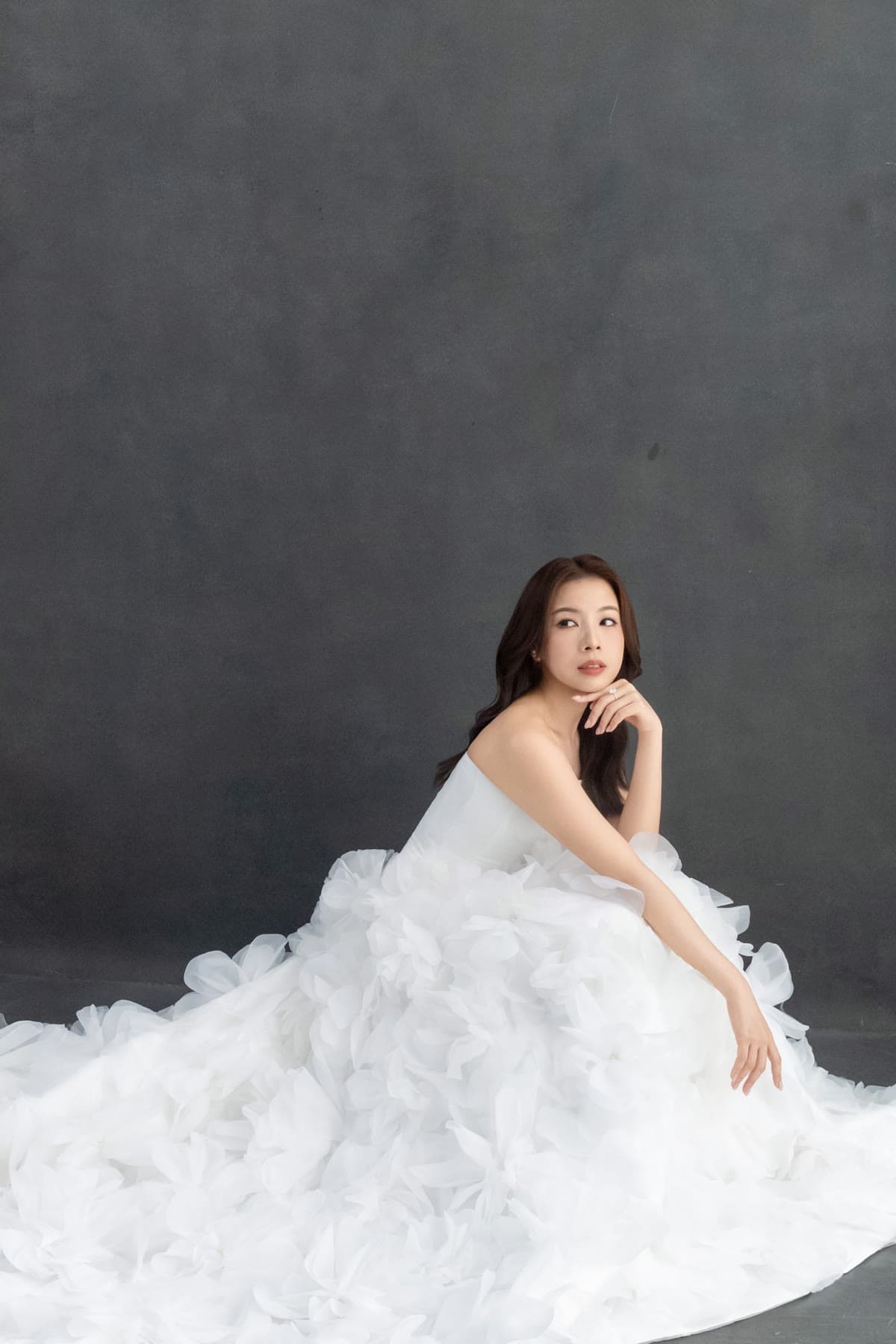 Natalie posing in her wedding gown against a pale studio backdrop