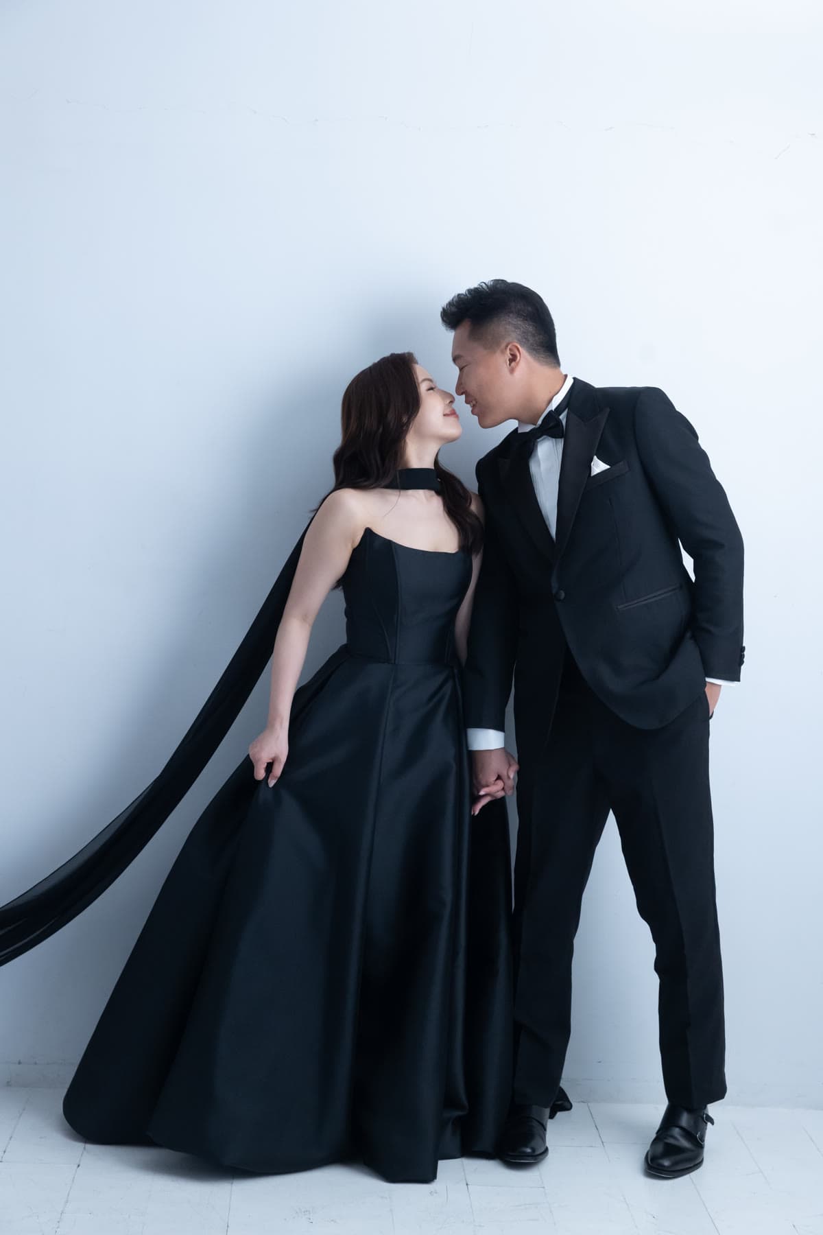Natalie and Bryan posing together against a pale studio backdrop