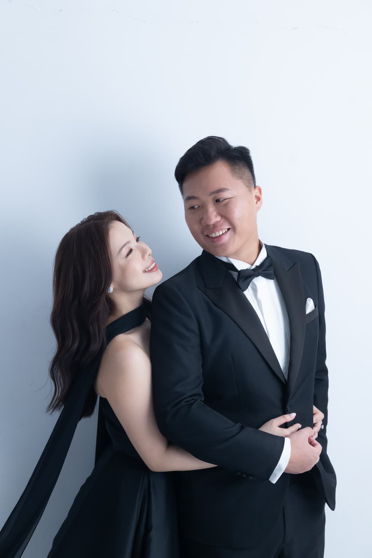 Natalie and Bryan smiling at one another in black formalwear
