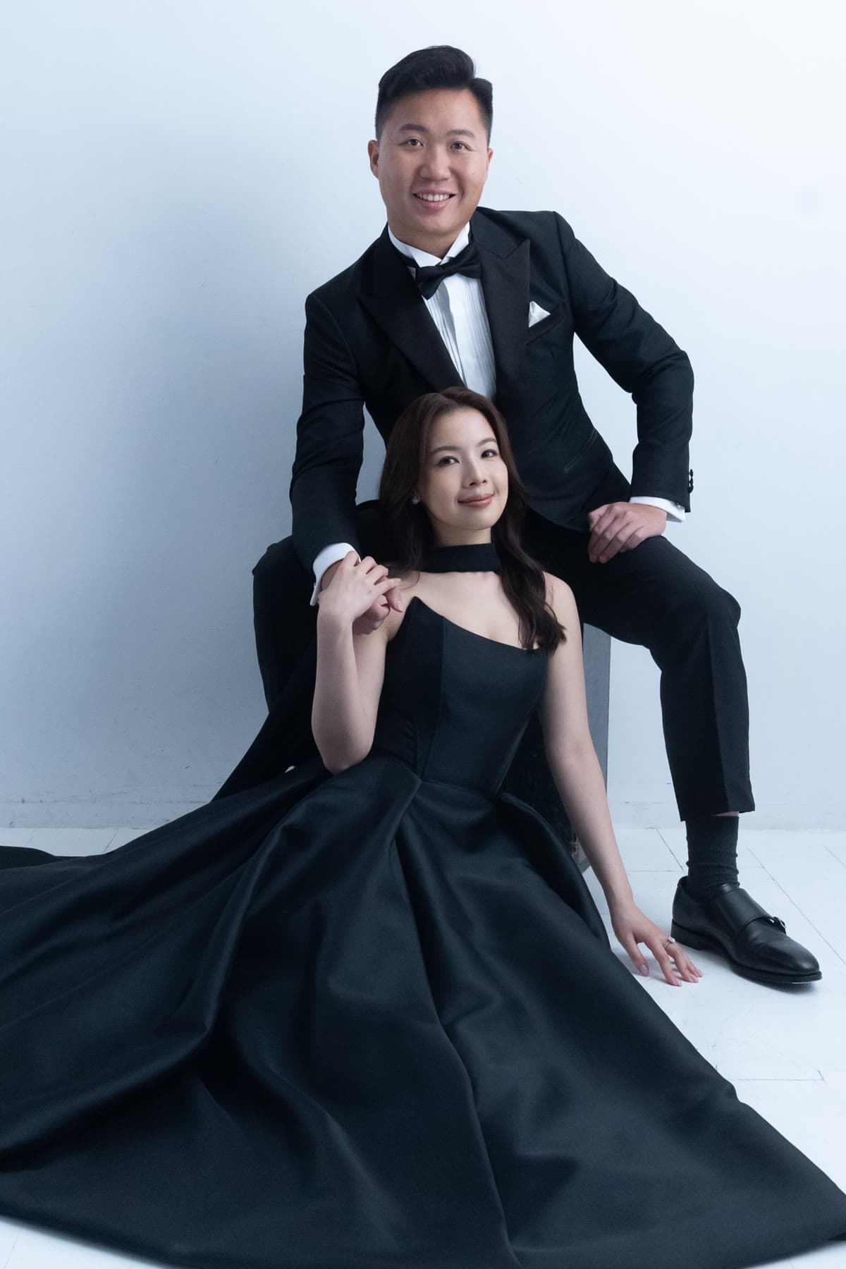 Natalie seated in a black gown with Bryan standing behind her