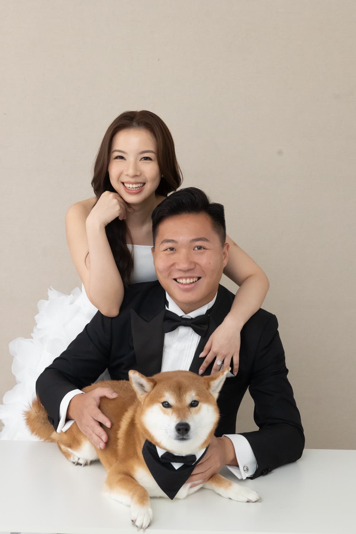 Natalie and Bryan smiling with their dog in a studio portrait