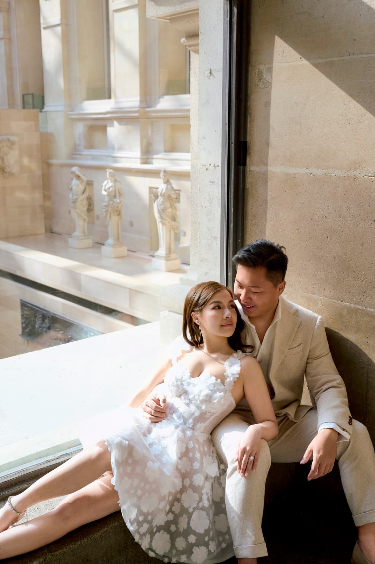 Natalie and Bryan seated together beside a sunlit gallery window